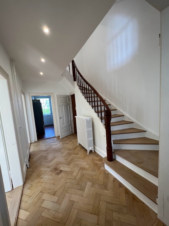 Escalier d’entrée associé à un parquet, marches en bois et contremarches blanches